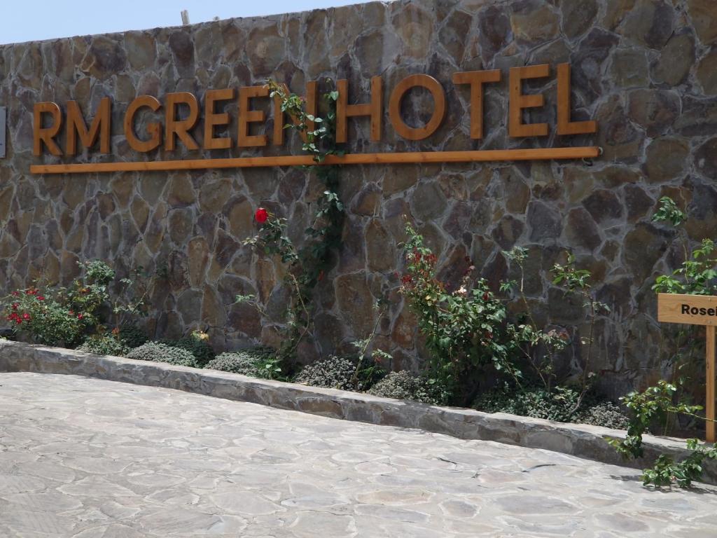 un panneau indiquant l'hôtel ryan vert sur un mur de pierre dans l'établissement RM Green Hotel, 