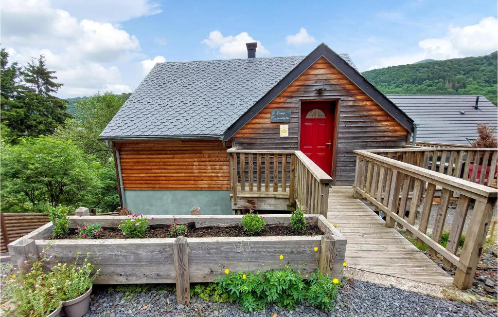 a cabin with a red door and a wooden deck at 4 Bedroom Cozy Home In Mont-dore in Le Mont-Dore
