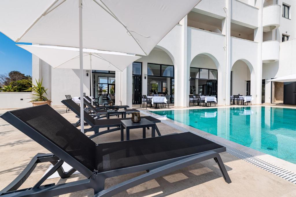a pool with two lounge chairs and an umbrella at Miramare Hotel in Zadar