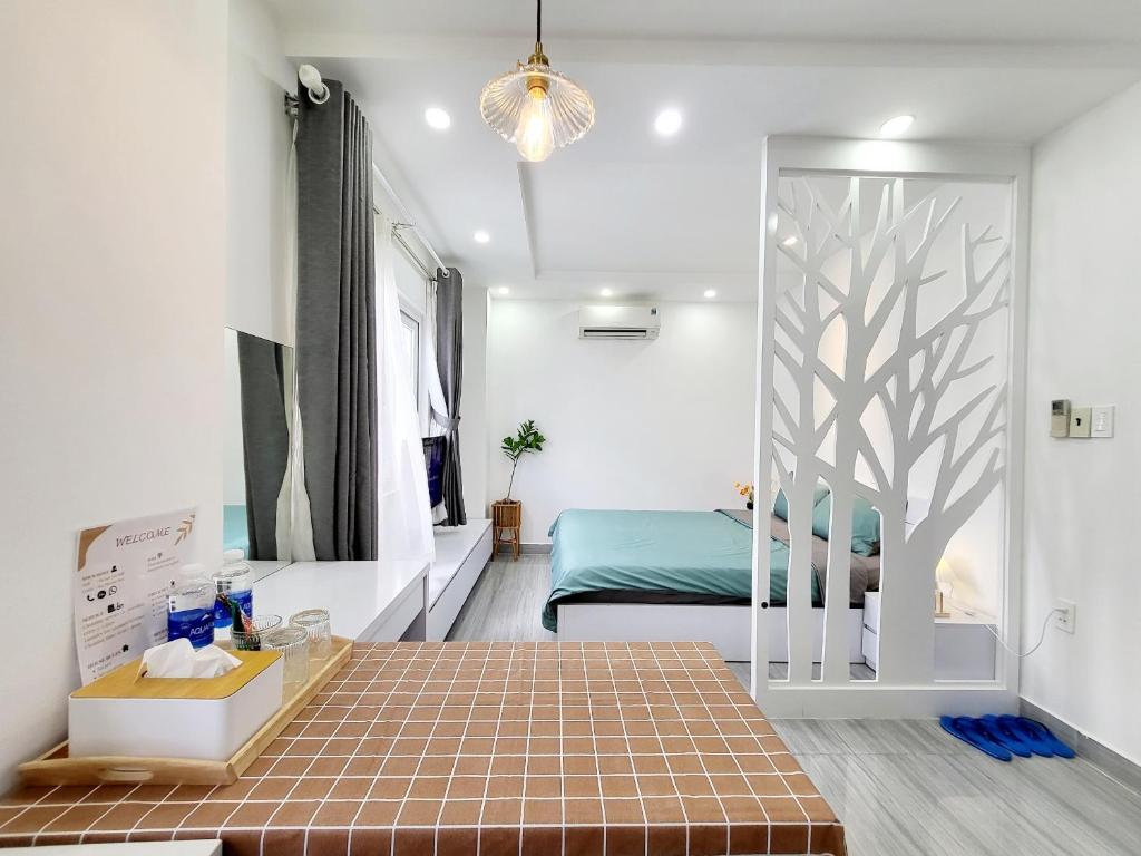 ein Schlafzimmer mit einem Bett und ein Zimmer mit einem Baum an der Wand in der Unterkunft MơMơ Residence in Ho-Chi-Minh-Stadt