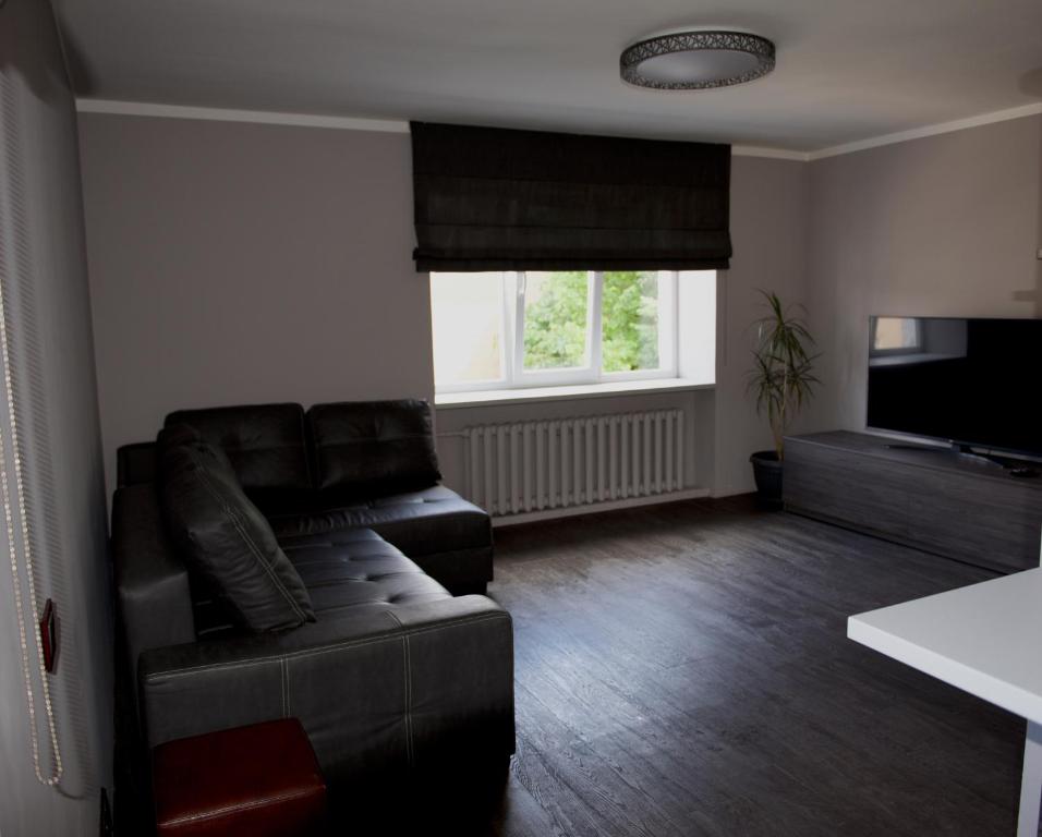 un soggiorno con divano e TV a schermo piatto di Mucenieku Apartamenti a Kuldīga