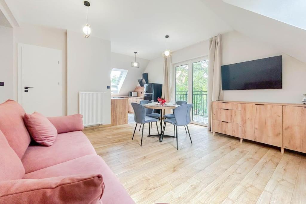 a living room with a pink couch and a table at Apartament Ptasi Śpiew 2 in Rabka-Zdrój