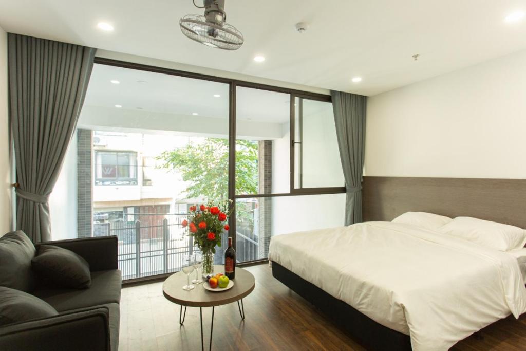 - une chambre avec un lit, une table et un canapé dans l'établissement The Carnation Apartment 02, à Hanoï