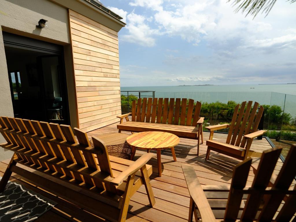 dos sillas y una mesa en una terraza con el océano en Le pavillon d'Eole-loft vue mer exceptionnelle, en Réville