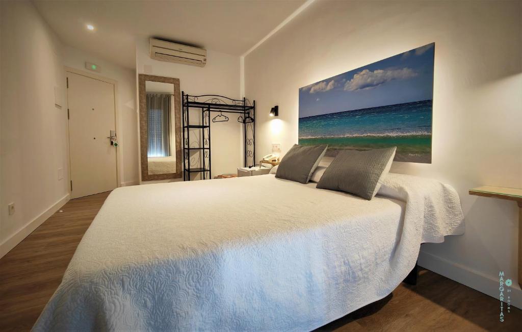 1 dormitorio con 1 cama con una pintura en la pared en Margaritas 21 Rooms, en Tarifa