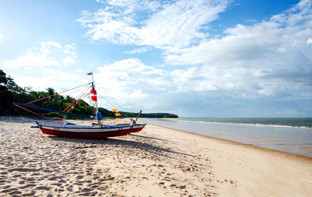 un pequeño barco sentado en una playa de arena en Pousada das Estrelas, en Joanes