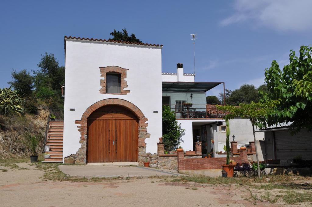 a white house with a wooden door in front at Acogedor apartamento en entorno rural in Massanas