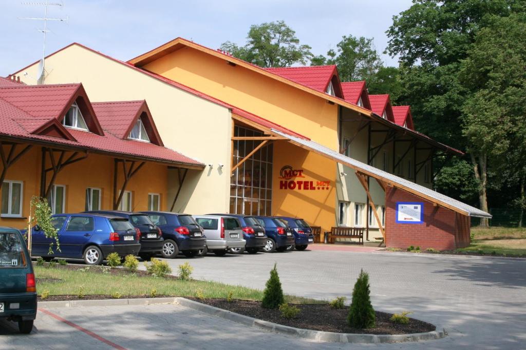 un edificio con coches estacionados en un estacionamiento en Hotel MCT, en Żerków