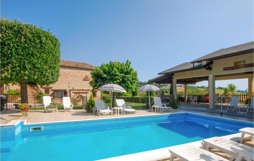 - une piscine avec des chaises et des parasols à côté d'un bâtiment dans l'établissement Gorgeous Apartment In Monte Rinaldo With Wifi, à Monte Rinaldo