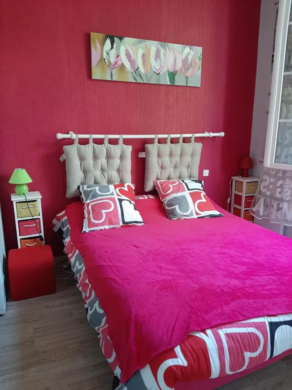 une chambre rouge avec un lit rose avec des oreillers dans l'établissement Bel appartement-terrasse Ronce-les-Bains, à La Tremblade