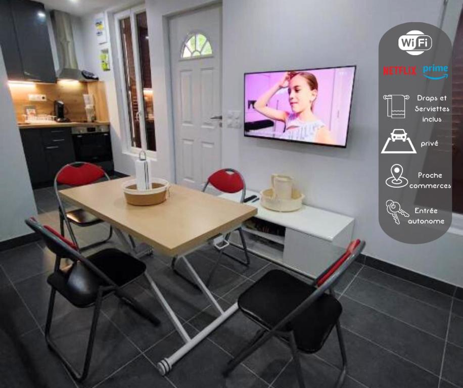 una sala da pranzo con tavolo e TV a parete di Petite maison avec jardin a Montluçon