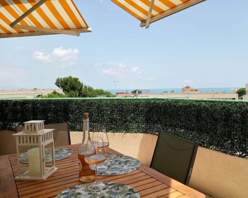 - une table avec une bouteille de vin et deux verres dans l'établissement Superbe appartement ensoleillé - Vue mer, Clim et Parking, à Villeneuve-Loubet