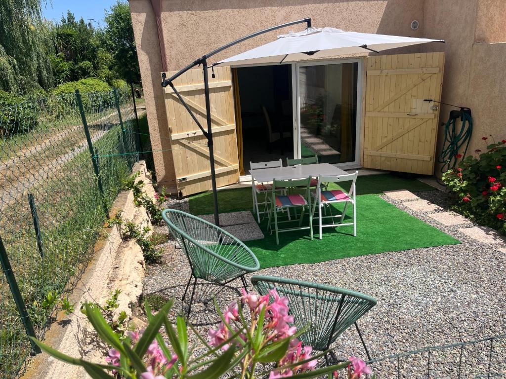 a garden with a table and chairs and an umbrella at Studio tout équipé à la nuitée ou plus,proche aéroport Bastia in Lucciana