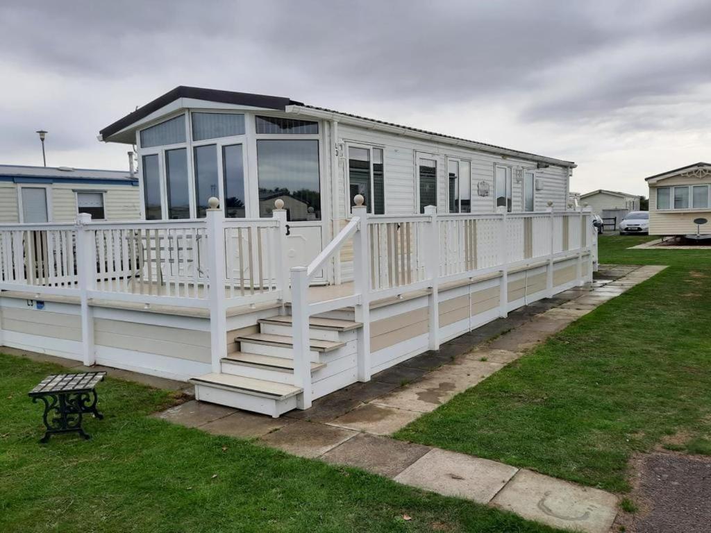 ein großes weißes Haus mit einer Veranda und einer Treppe in der Unterkunft Millfields 4 berth caravan DG & CH family's only and lead person must be over 30 in Ingoldmells