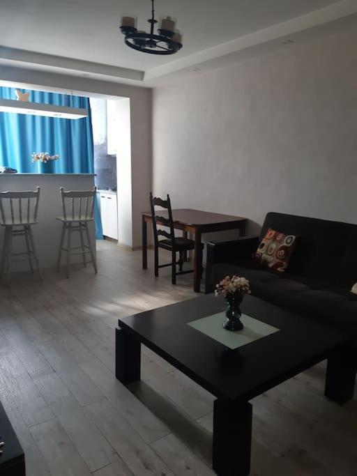 een woonkamer met een zwarte bank en een tafel bij Lovely_apartment in Tbilisi City