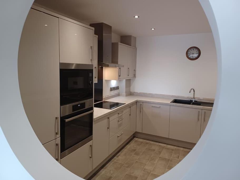a kitchen with white cabinets and a clock on the wall at Admiral's View - Apartment 1 in Scarborough