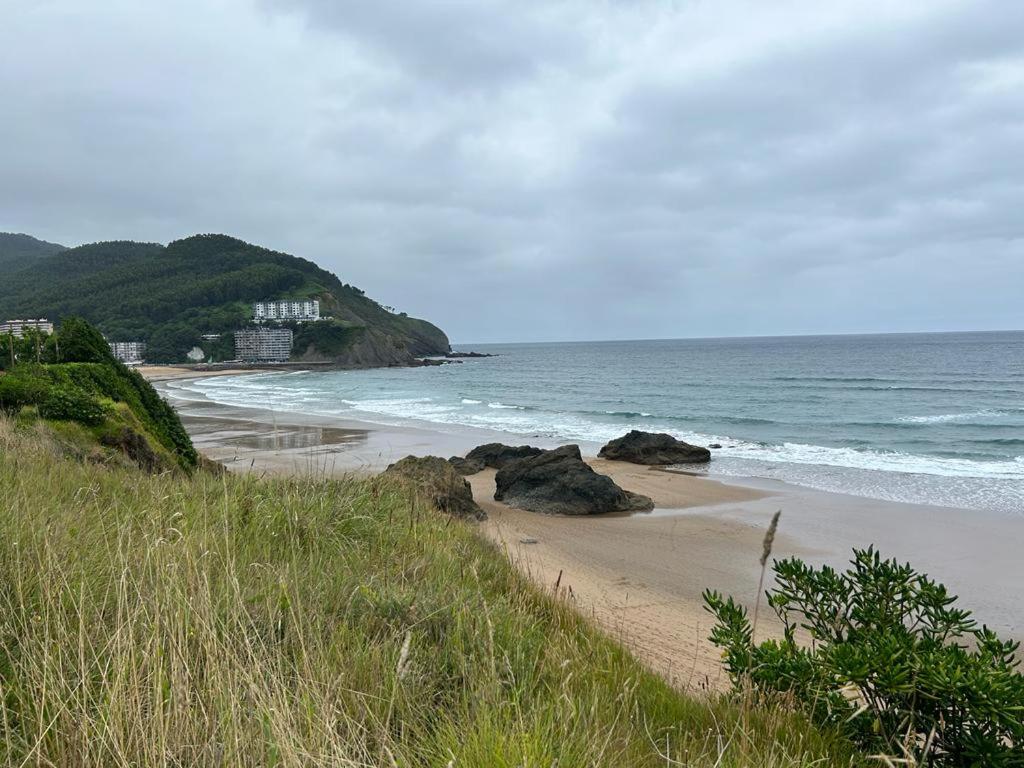 a sandy beach with rocks and the ocean at Bakio Beach House in Bakio