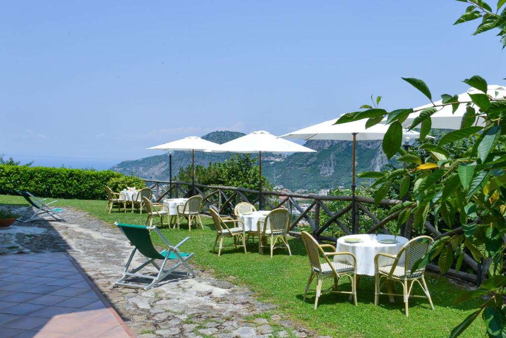 een groep stoelen en tafels met witte parasols bij Villevieille in Piano di Sorrento