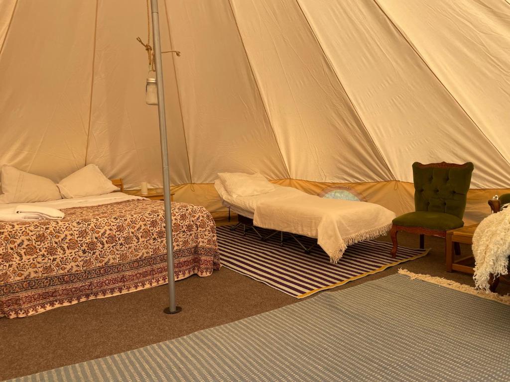 a bedroom with a tent with a bed and a chair at Luxury glamping at Kipeni 