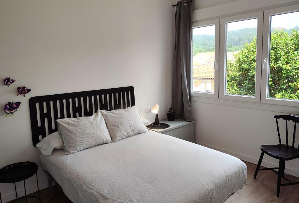 a bedroom with a white bed and a window at Voga Voga in Corcubión