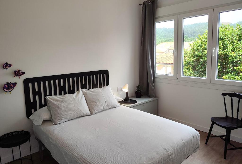 1 dormitorio con cama blanca y ventana en Voga Voga en Corcubión