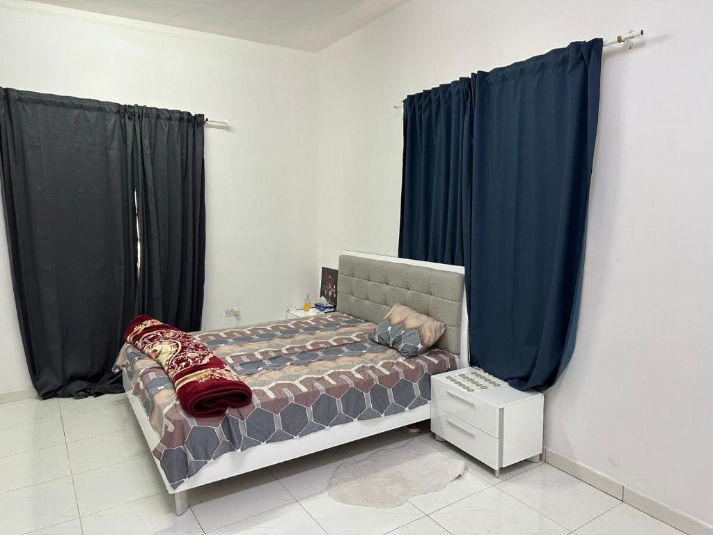 1 dormitorio con 1 cama con cortinas azules en لولي قست هاوس, en Al Ain