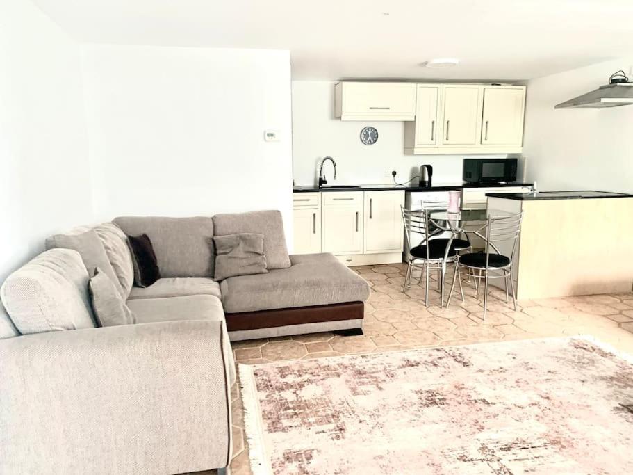 a living room with a couch and a kitchen at Lovely one bedroom flat next to our family home in Dallington