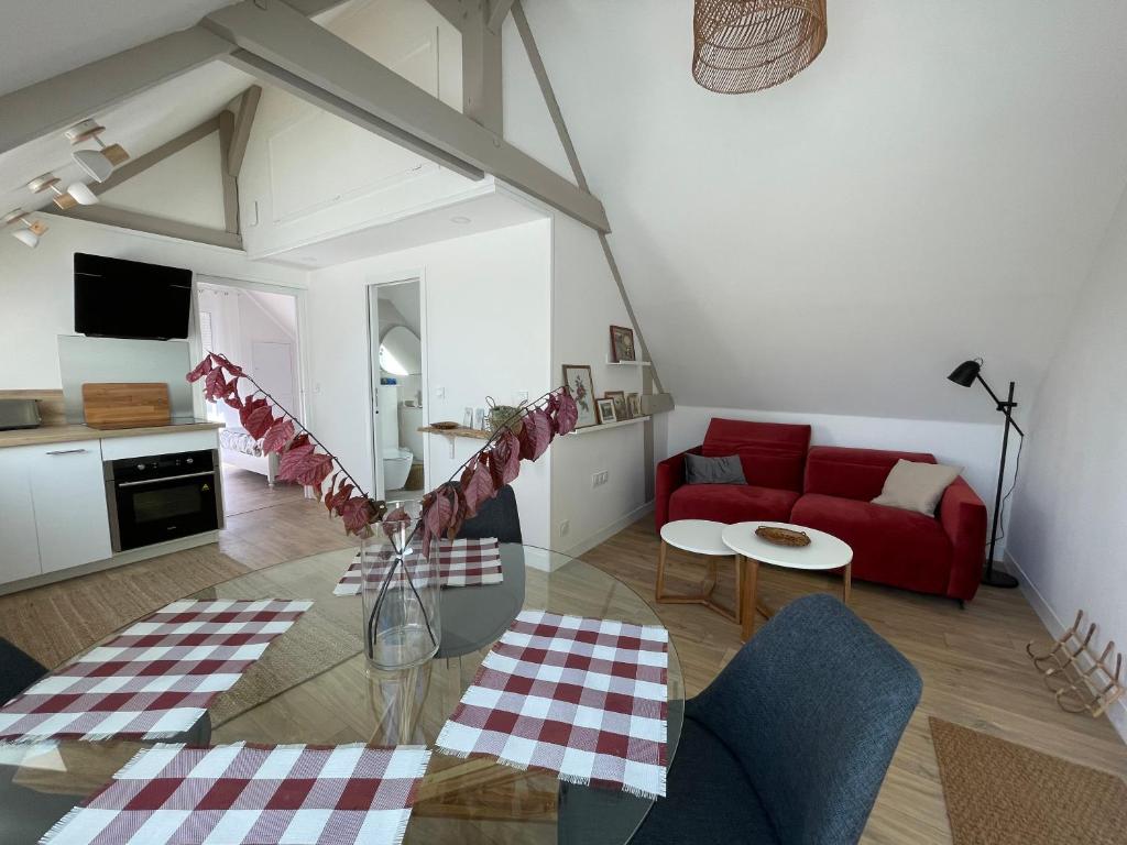 uma sala de estar com um sofá vermelho e uma mesa em Le Verger de Sophie em Sainte-Geneviève-lès-Gasny