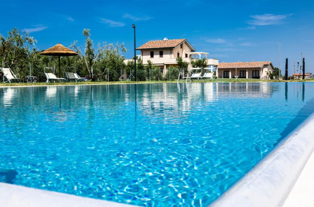a swimming pool with blue water in front of a house at Podere Giovanni Olivo in Tarquinia