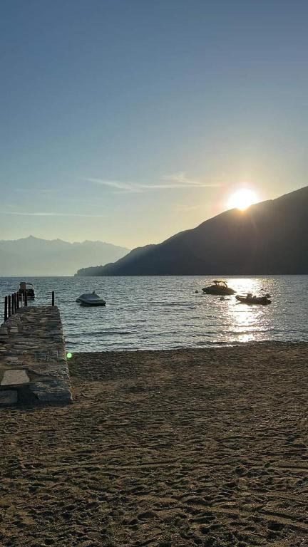 a beach with the sun setting over a body of water at Appartamento AZZURRO in Cannobio
