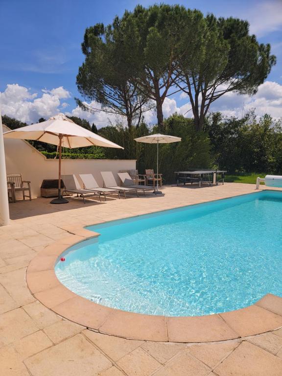 una piscina con due ombrelloni e un tavolo di Maison au calme vaste jardin a Mazan