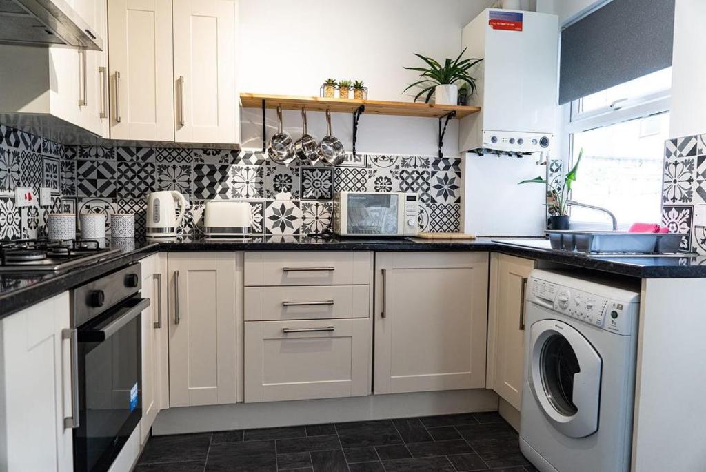 eine Küche mit weißen Schränken, einer Waschmaschine und einem Trockner in der Unterkunft The Beatles house - Penny Lane - Contractors -Relocating in Liverpool