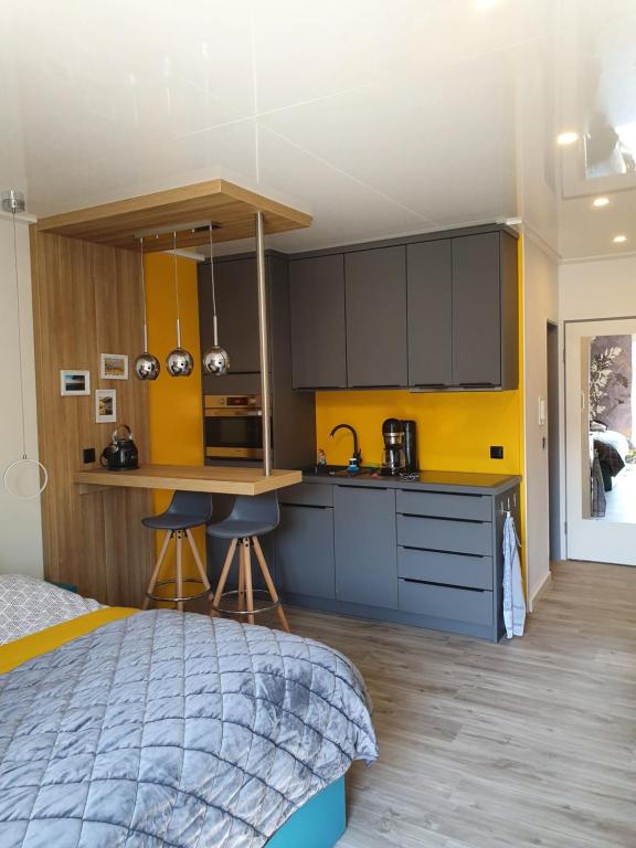 a bedroom with a bed and a kitchen with yellow walls at Kleine Milchbar in Norderney