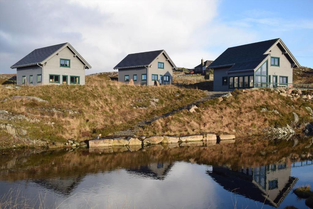 a row of houses on a hill next to a body of water at Arran Lodge, Isle of Harris in Manish