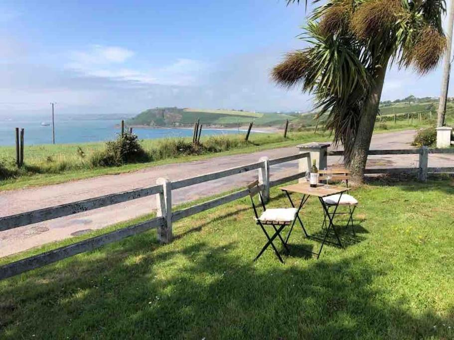 a table and chairs next to a fence and a beach at Harbour View Cottage, Rochespoint, Cork Harbour in Midleton