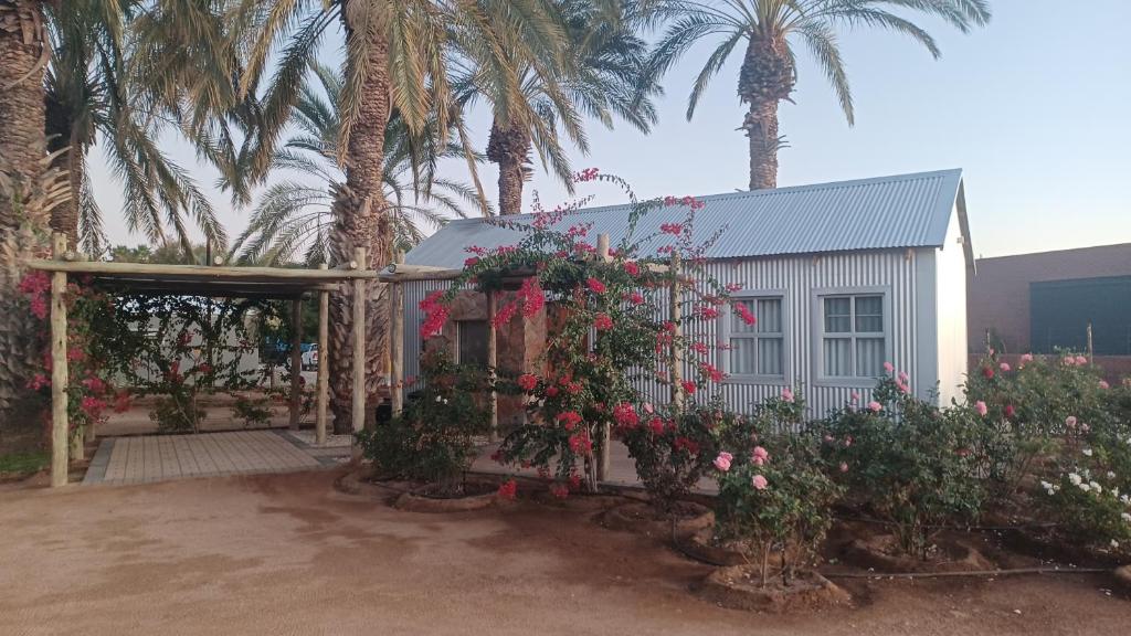 a white building with palm trees and flowers at Gazelle Estate in Kakamas
