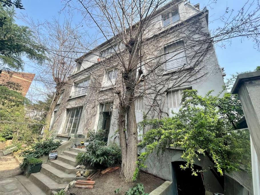 un grand bâtiment en pierre avec un arbre devant dans l'établissement Logement en Hôtel Particulier à 3mns de Paris et de 3 sites olympiques avec grand jardin et Jacuzzi, à Boulogne-Billancourt