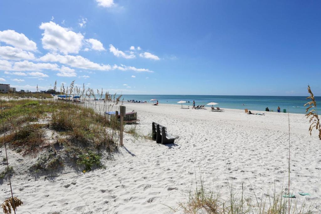 a sandy beach with people sitting on the beach at C6-Manatee in St. Pete Beach