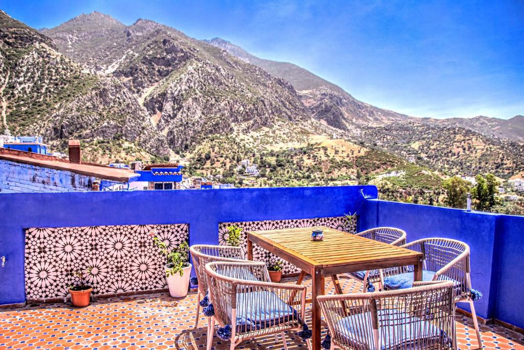 a table and chairs on a blue balcony with mountains at Old world charm, modern comfort in Chefchaouene