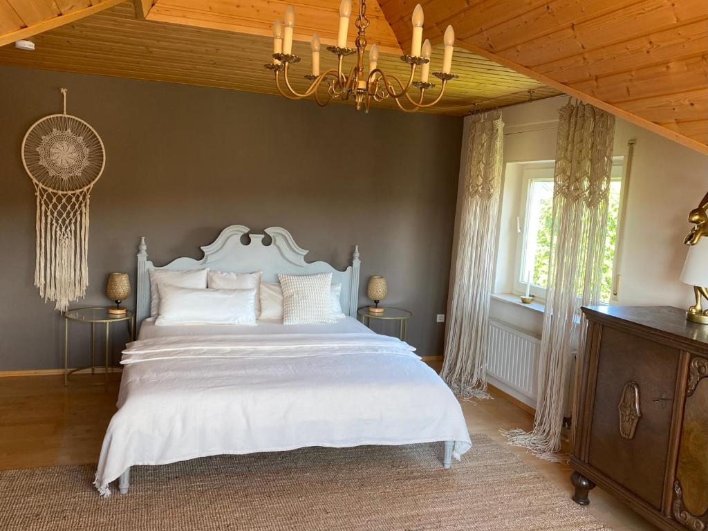 a bedroom with a large white bed and a chandelier at bei Servays in Eppingen