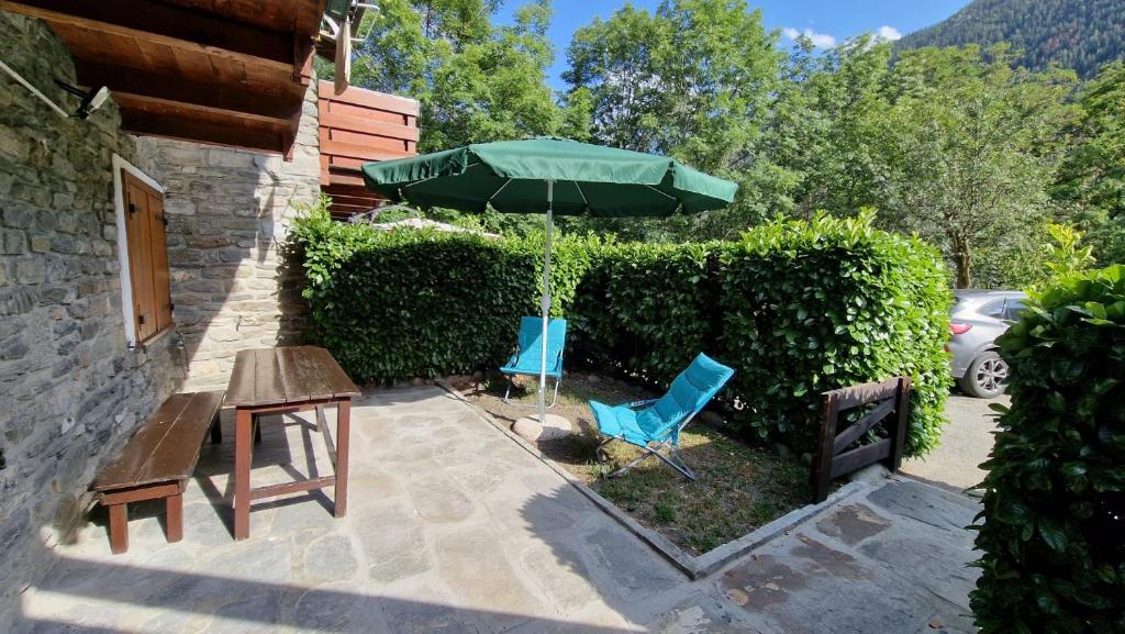eine Terrasse mit einem Tisch, einem grünen Sonnenschirm und Stühlen in der Unterkunft Espoire - villar vda la salle cir 26 in Villair