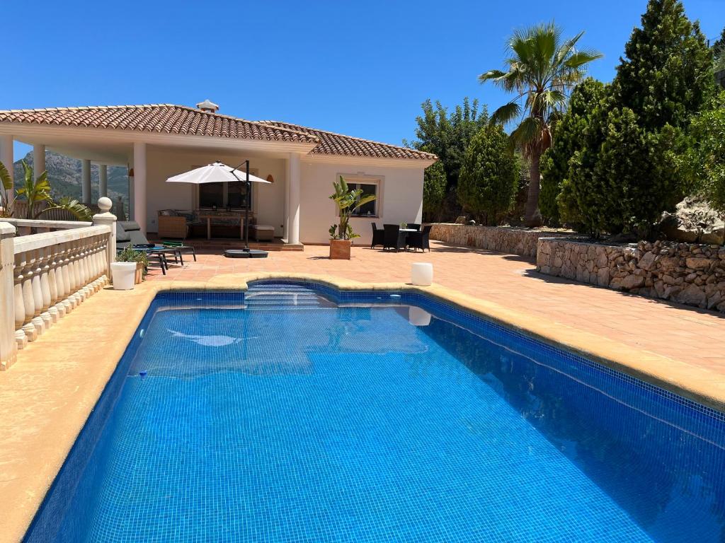 a swimming pool in front of a house at Denia Dream Seaview Golf, Tennis & Beach Villa in Muntanya la Sella