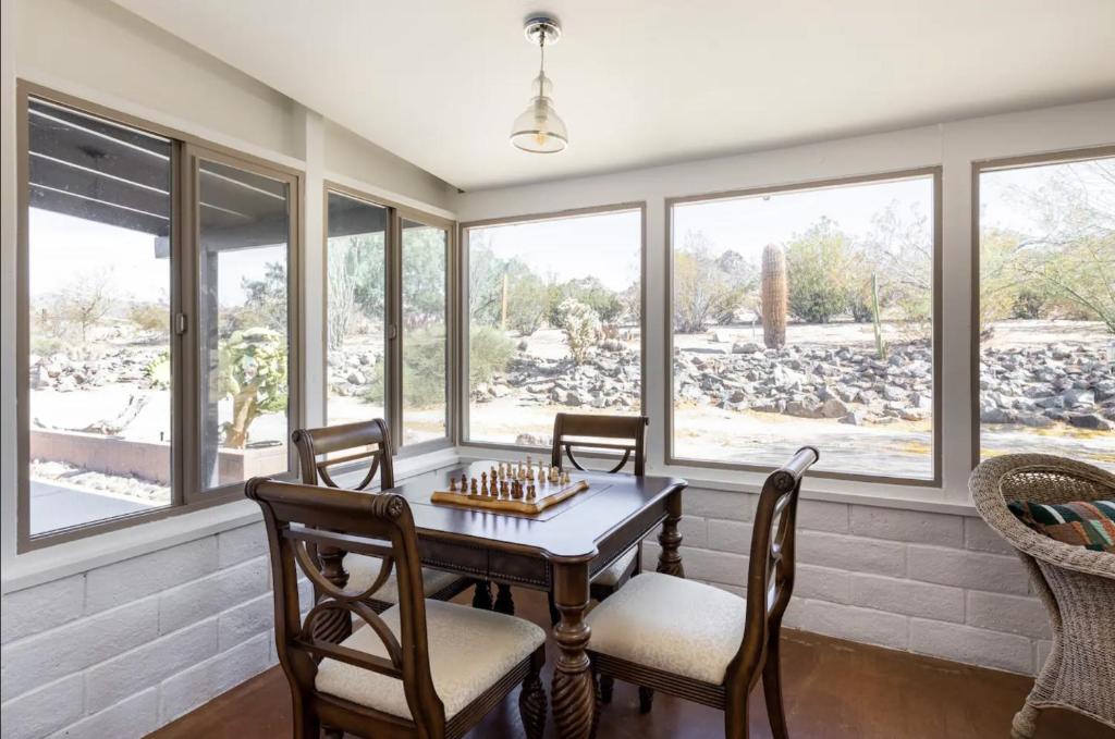 a dining room with a table and chairs and windows at The Outpost Joshua Tree: Hot Tub, GameRoom, JTNP in Joshua Tree