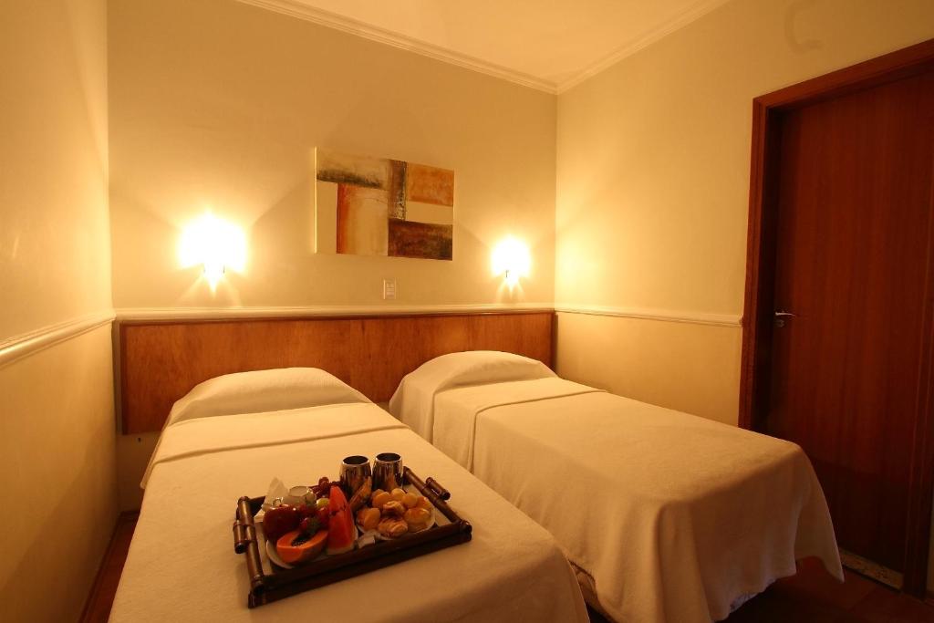 two beds in a hotel room with a tray of fruit at Scarpelli Palace Hotel in Sorocaba