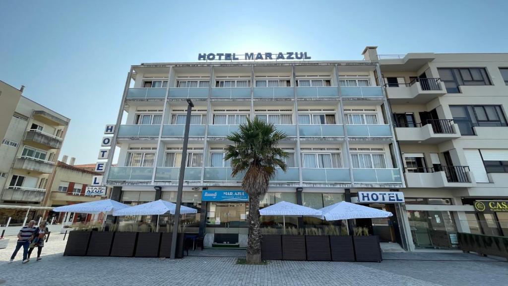 a hotel with a palm tree in front of a building at Hotel Mar Azul in Espinho