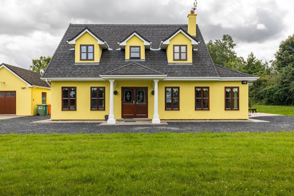 een geel huis met een zwart dak bij Yellow House in Westport