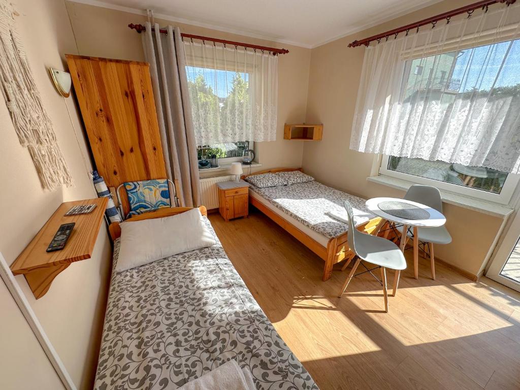 niewielka sypialnia z łóżkiem, biurkiem i stołem w obiekcie Joasia we Władysławowie