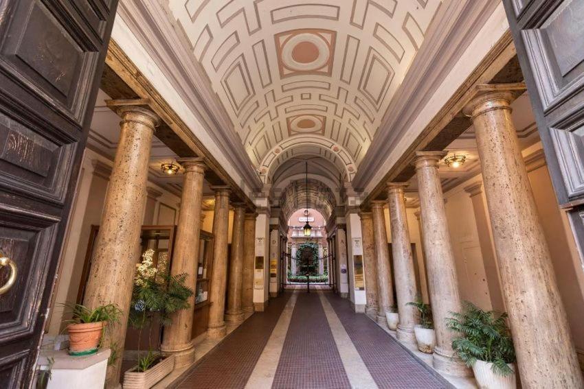 un couloir d'un bâtiment avec colonnes et plafond dans l'établissement Karisma Suites, à Rome