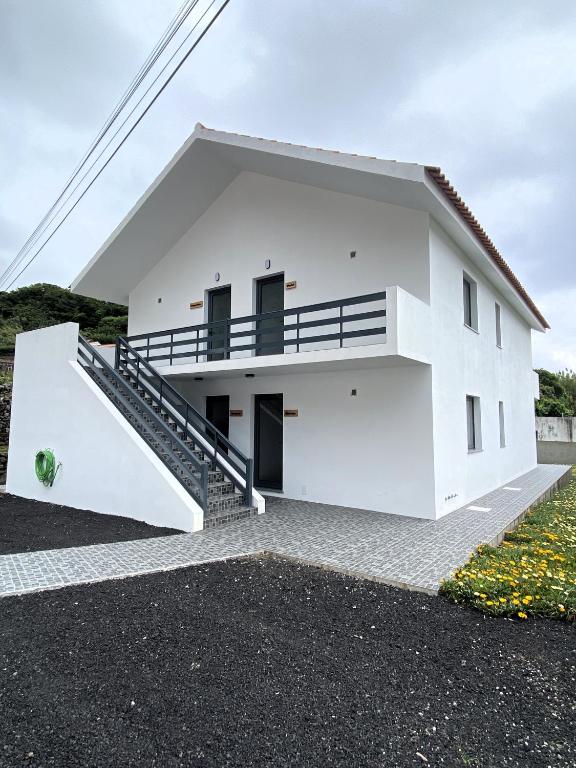a white house with a staircase in front of it at Apartamentos 4 estações in Faja Grande