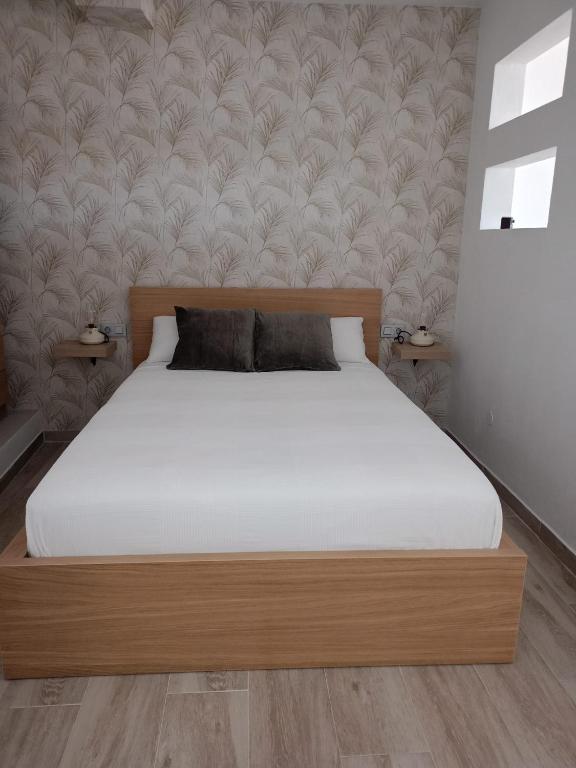 a bedroom with a bed with white sheets and a wall at La Lunita in Valverde